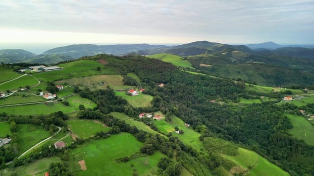 An aerial view shows a picturesque landscape with lush green hills, charming homes, and beautiful scenery