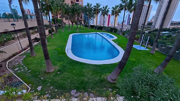 A beautiful pool area framed by palm trees and stunning architecture, all under a serene, clear sky