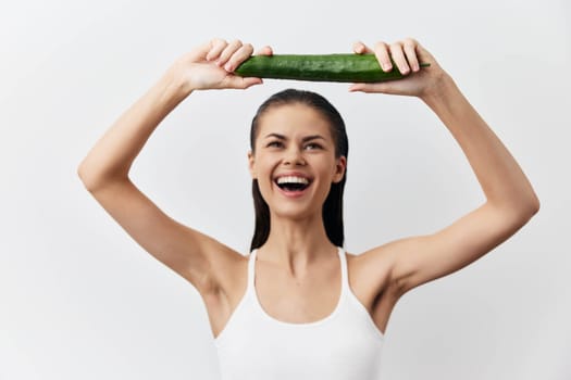 joyful woman holding a cucumber above her head, showcasing a vibrant smile She represents the essence of healthy living and natural beauty The bright white background emphasizes freshness