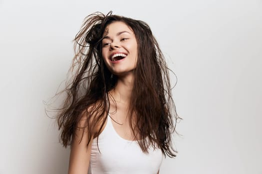 cheerful young girl with flowing hair laughing joyfully, featuring a fresh and lively expression on a neutral light backdrop, symbolizing beauty, freedom, and positivity