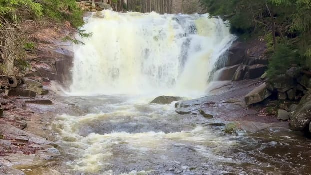 A breathtakingly stunning waterfall gracefully cascading over rugged rocks, embraced by flourishing lush greenery