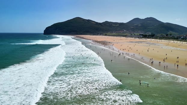 An absolutely stunning beach scene showcasing rolling waves and countless beachgoers happily enjoying the sun