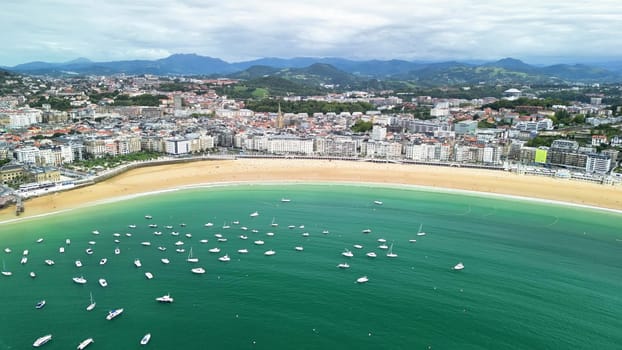 A stunning aerial view of a coastal town with sandy beaches and boats sailing on a sunny, serene day