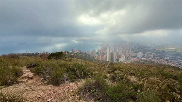 A breathtaking landscape beautifully showcasing a vibrant coastal city adorned with dramatic clouds and lush greenery