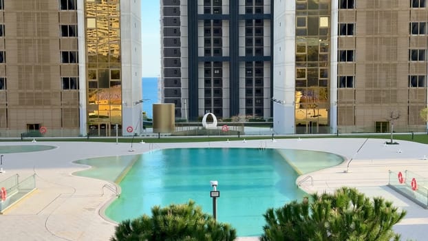 Stunning, intricately designed modern buildings reflect beautifully in the tranquil pool of a luxurious urban complex