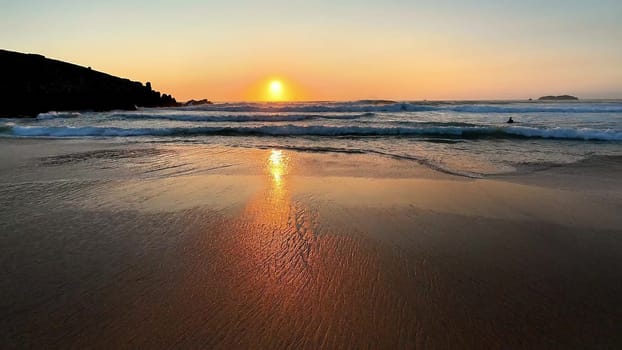 A breathtaking sunset beautifully reflecting on the calm beach, evoking a deep sense of tranquility and natural beauty