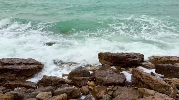 Experience the breathtaking beauty of waves crashing against rocky formations along a serene coastline