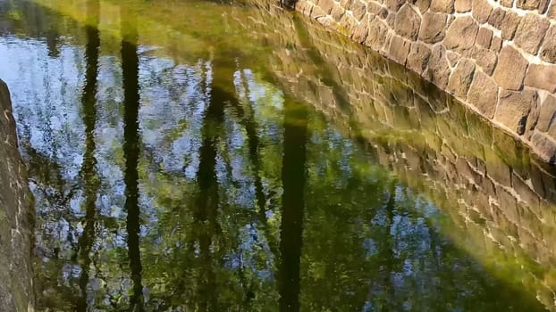 Enjoy a serene view of a flowing stream, a stone wall, and lush grass, creating a picturesque scene