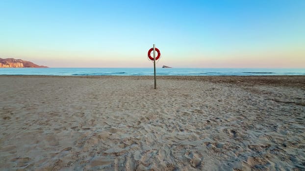 A tranquil and peaceful beach scene at sunset showcasing a bright lifebuoy resting on soft, warm sand