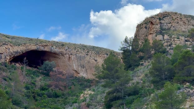Embark on an adventure to explore a breathtaking cave beautifully surrounded by vibrant greenery and scenic hills