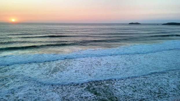 A stunning view of gentle ocean waves rolling gently onto a serene and tranquil beach as the sun sets beautifully