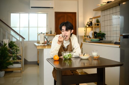Young man in apron enjoying a healthy breakfast at home.