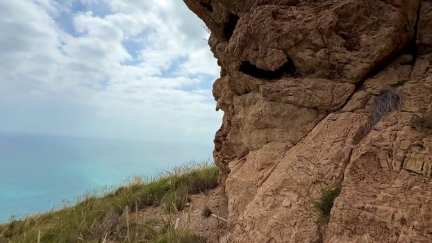 A breathtaking view of rugged rock formations overlooking a vibrant turquoise sea and a cloudy sky above