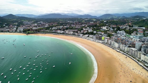 Enjoy stunning aerial views of a peaceful beach next to a busy city, perfect for relaxation during vacations