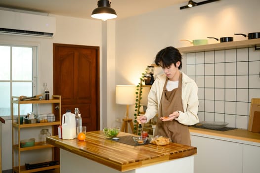 Young man in apron preparing a simple breakfast in a cozy modern kitchen.