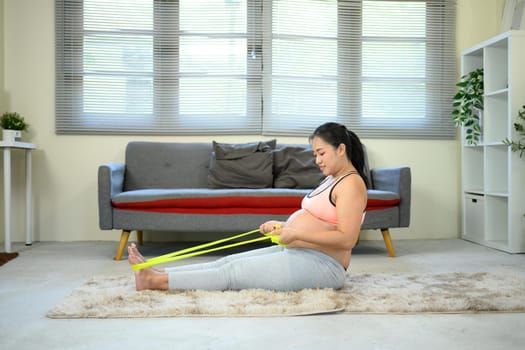 Pregnant woman exercising with resistance band staying active and healthy during pregnancy.