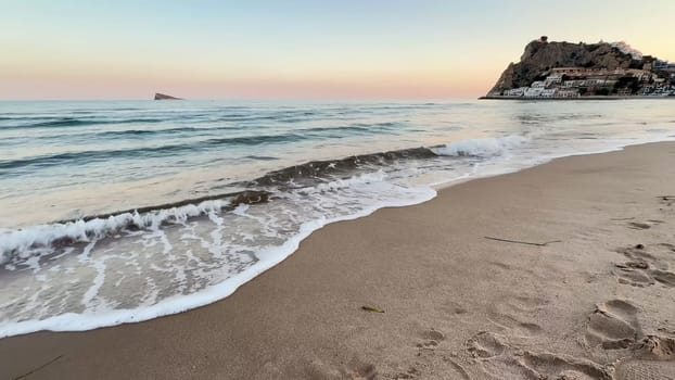 Imagine a truly peaceful beach scene, where gentle, calming waves meet a breathtaking sunset backdrop at dusk