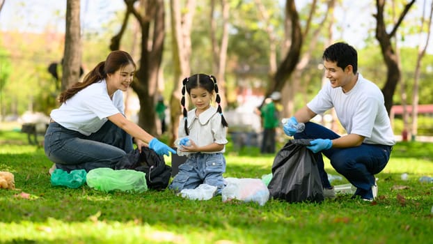 Happy family picking up litter together in a park for environmental conservation.