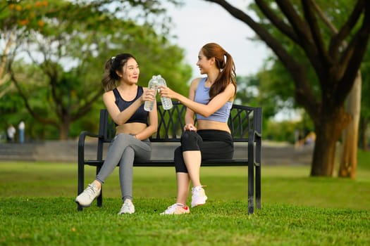 Cheerful female friends resting together after exercising outdoors.