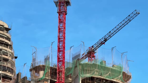 A vibrant construction site featuring cranes, scaffolding, and concrete structures under blue skies.