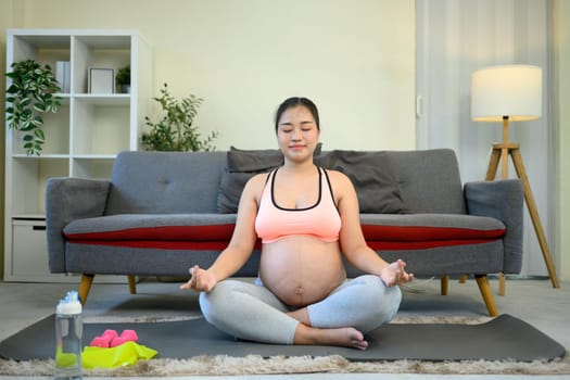 Pregnant woman practicing meditation at home for prenatal wellness.