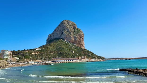 Experience breathtaking seaside scenery showcasing a majestic rock amid stunning turquoise waters beneath a clear sky