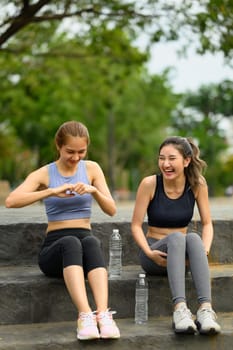 Cheerful female friends resting together after exercising outdoors.