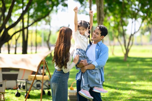 Family having fun at a campsite with tents in the background.