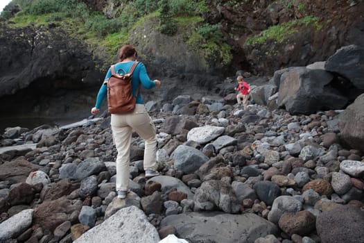 Mother and son exploring rocky beach, enjoying nature walk in volcanic landscape of canary islands
