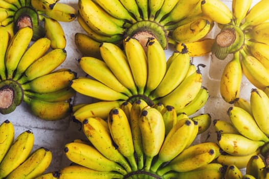 background of a harvest of ripe yellow bananas on a market stall. Tropical fruits in Asia
