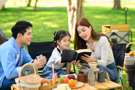 Parents and daughter camping in a forest park surrounded by nature and fresh food.
