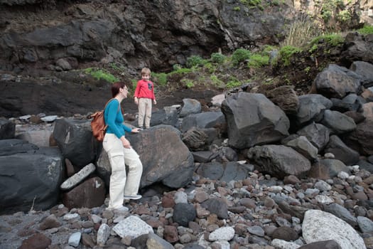 Mother and child navigating a rocky coastline, embracing the beauty of nature's rugged landscape