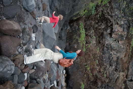 Mother and son carefully walking on volcanic rocks, enjoying a hike in a natural environment