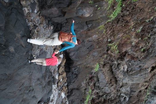 Mother and son walking and exploring volcanic caves holding hands