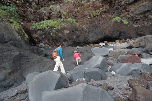 Mother and child carefully navigating a challenging volcanic landscape, showcasing the beauty of nature's rugged formations
