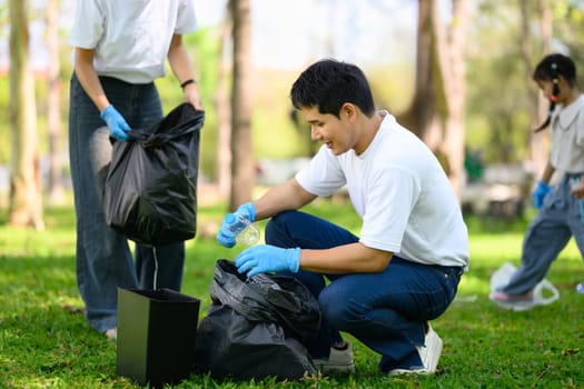 Happy family picking up litter together in a park for environmental conservation.
