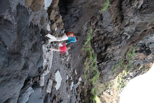 Two hikers exploring volcanic canyon walking on rocky path