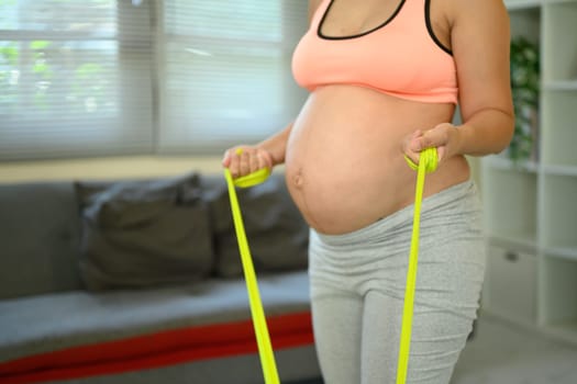 Pregnant woman exercising with resistance band staying active and healthy during pregnancy.