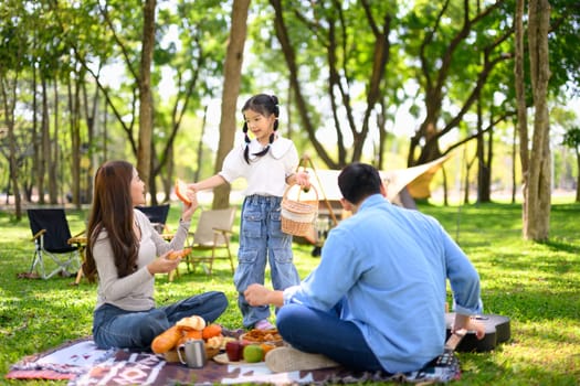 Cheerful family sharing food during a relaxing outdoor camping trip.