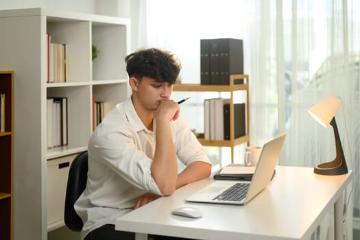 Focused male freelancer concentrating on work in a bright home office
