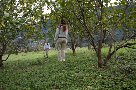 Mother and daughter enjoying a playful moment in a picturesque lemon orchard on a hillside