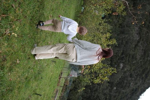Mother and son enjoying a leisurely stroll through a vibrant green meadow, near fruit trees and a lush forest