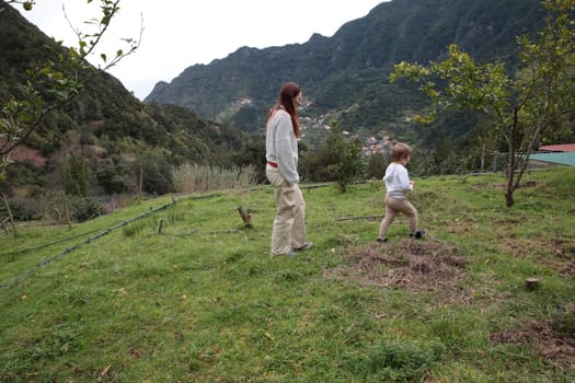 Mother and son farmers walking in fruit orchard with mountain view in madeira island, portugal