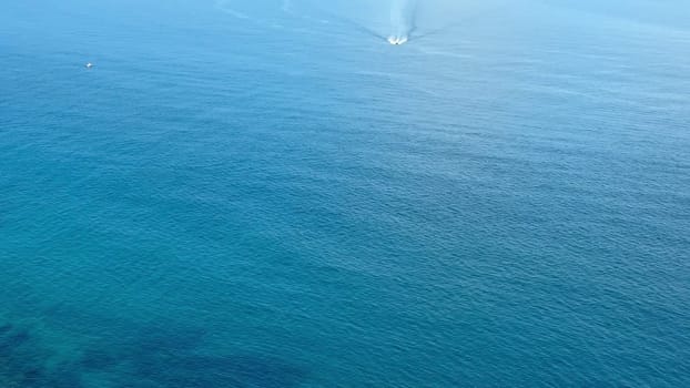 This stunning aerial photo captures serene ocean waves and a boat near a beautiful coastal landscape