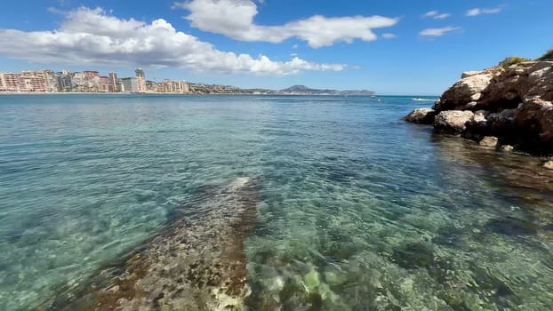 A stunning coastal scene with clear waters and a vibrant city skyline under a bright sunny blue sky