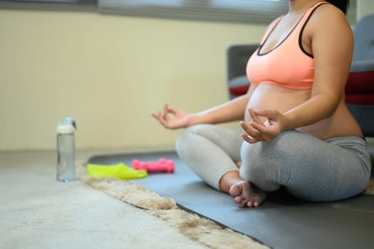 Pregnant woman practicing meditation at home for prenatal wellness.