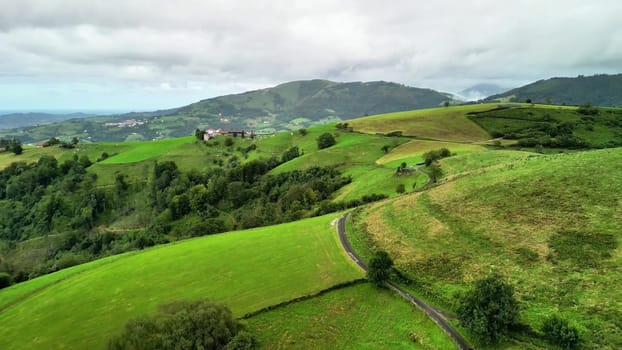 Gorgeous aerial view showcasing rolling green hills, meandering paths, all set beneath a beautifully cloudy sky