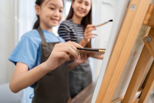 A delightful moment of a mother and daughter painting side by side, sharing creativity and love in their artistic journey.
