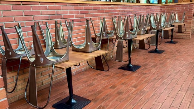In a restaurant setting, chairs are meticulously stacked on tables, showcasing a modern design aesthetic and decor