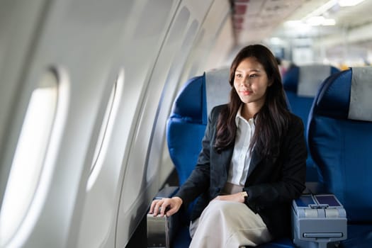 A young businesswoman sitting quietly on an airplane, reflecting on her journey while enjoying the flight.